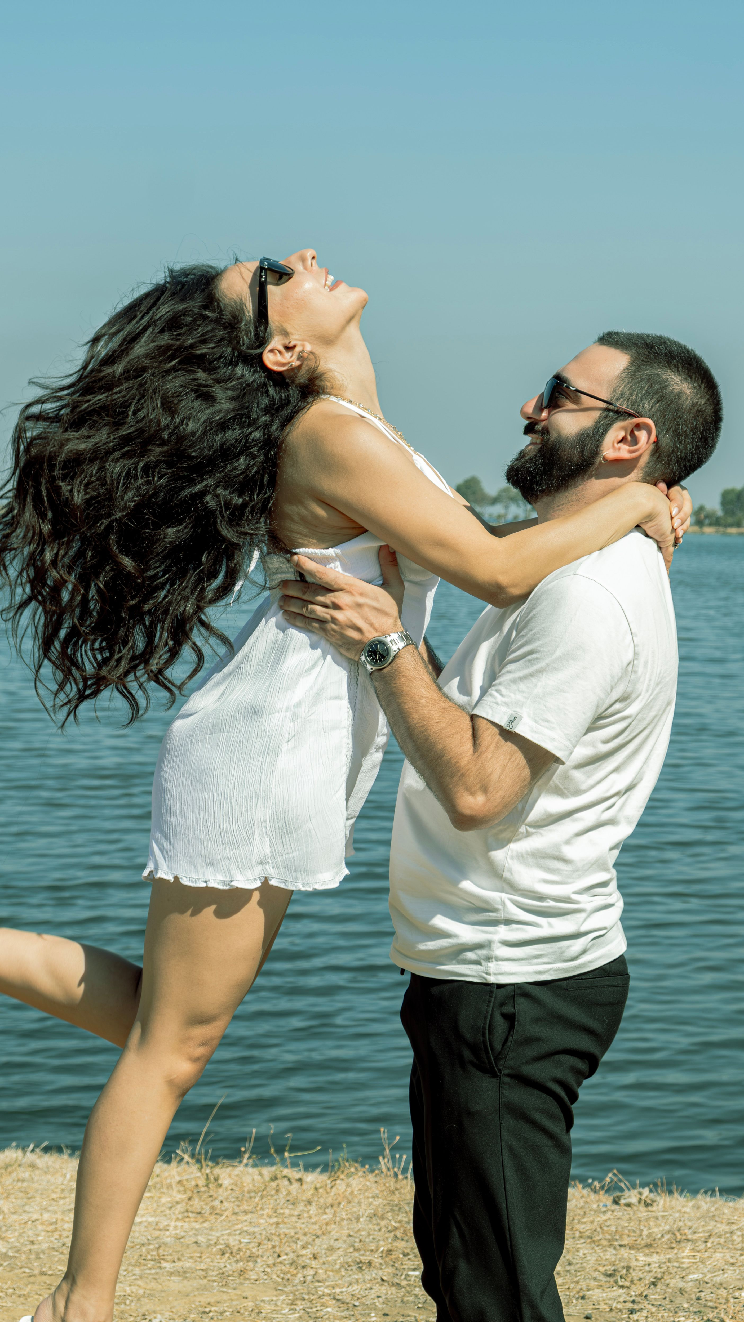 Sophia and Daniel laughing together by the water on a sunny day